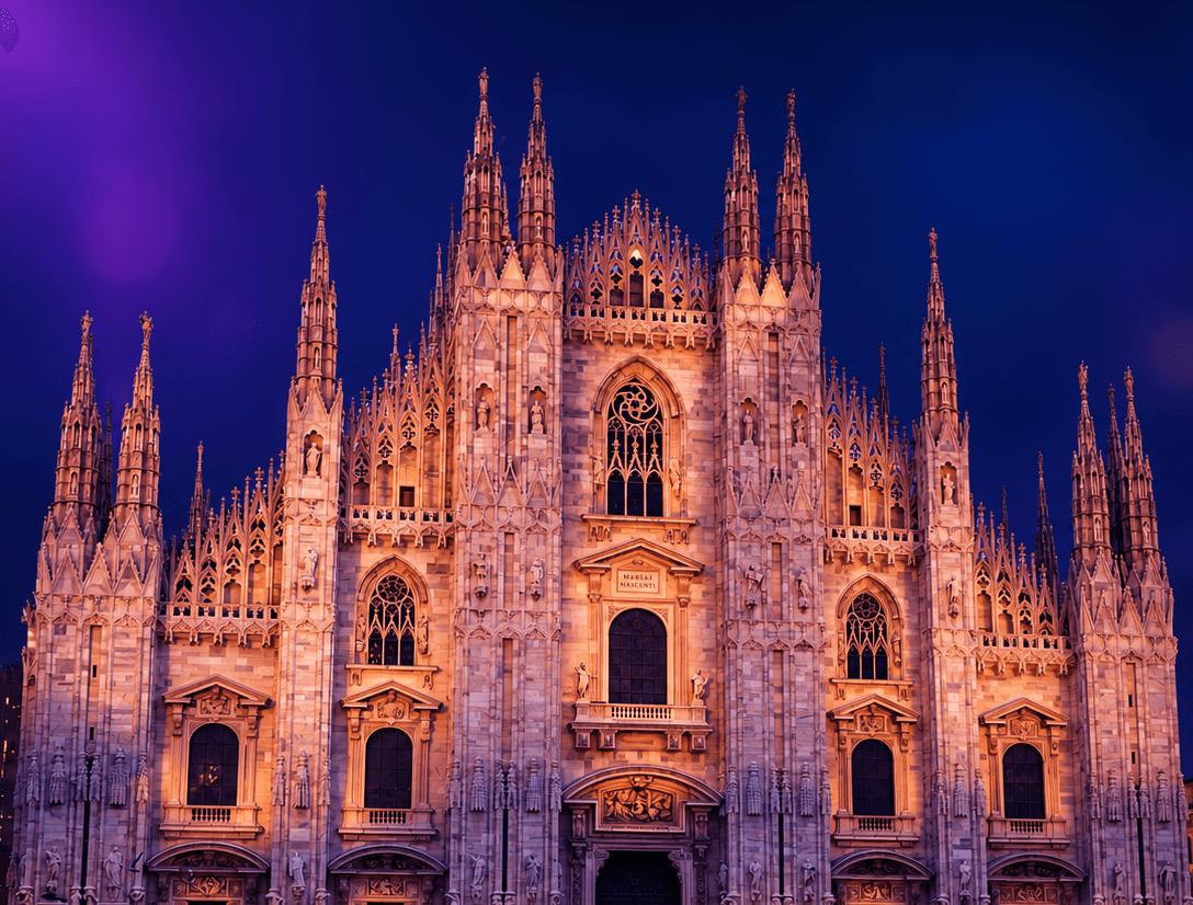 A floodlit Gothic cathedral facade against a deep blue and purple night sky